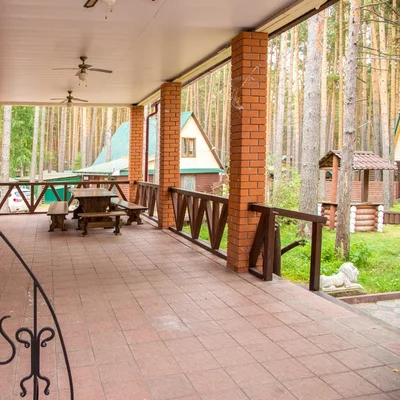 Крытая терраса с деревянной мебелью и кованым ограждением — снять дом для банкета, Усадьба — отдых за городом